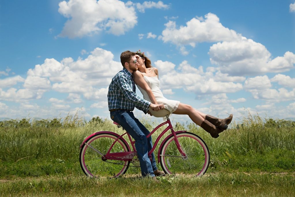 A couple riding a bike in a scenic field.
