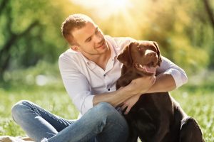 A man is sitting on the location with his dog.