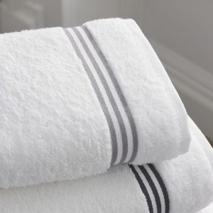 A stack of white towels with a black stripe demonstrates a perfect balance between simplicity and elegance.