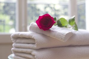 A stack of white towels with a red rose delicately balanced on top.