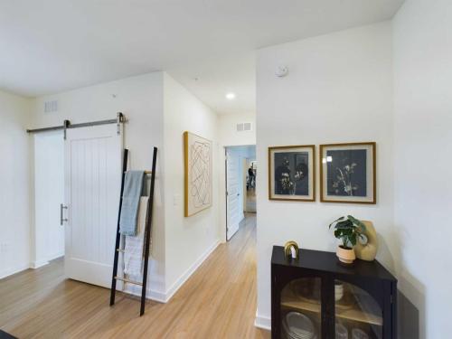 Apartments in Thompson’s Station Interior room with light wood flooring, white walls, a black cabinet, wall art, a ladder with towels, and a sliding barn door. Sanctuary Bluff Apartments in Thompson’s Station