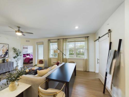 Apartments in Thompson’s Station Modern living room with light-colored furniture, a ceiling fan, large windows, and a sliding barn door leading to a bedroom. Sanctuary Bluff Apartments in Thompson’s Station