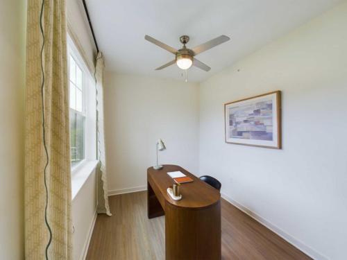 Apartments in Thompson’s Station A minimalist office with a wooden desk, chair, lamp, and notebook. Ceiling fan and abstract art on the wall. Large window with curtains on the left. Sanctuary Bluff Apartments in Thompson’s Station