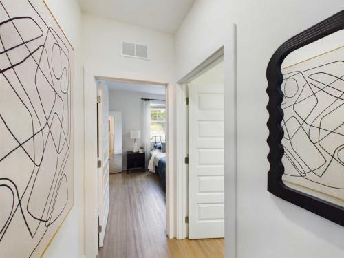 Apartments in Thompson’s Station Hallway with abstract artwork on the walls, leading to a bedroom with a window. A decorative mirror is on the right. Sanctuary Bluff Apartments in Thompson’s Station