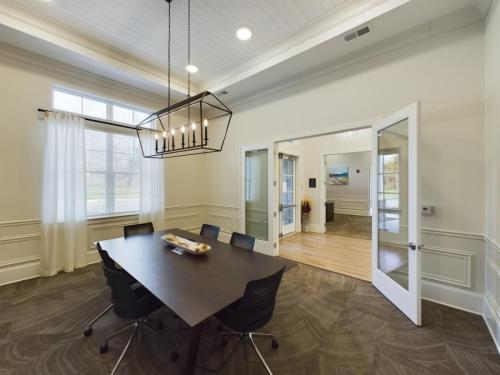 Apartments in Thompson’s Station A modern conference room with a rectangular table, six chairs, and a geometric chandelier. Glass double doors open to an adjoining room with wood flooring. Sanctuary Bluff Apartments in Thompson’s Station