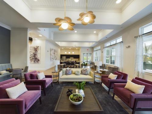 Apartments in Thompson’s Station Modern living room with high ceilings, large windows, and contemporary furniture, including purple armchairs, a beige sofa, and a wooden coffee table decorated with green plants. Sanctuary Bluff Apartments in Thompson’s Station